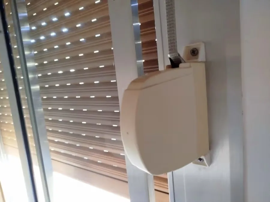 Mini roller shutter strap winder installed next to a window